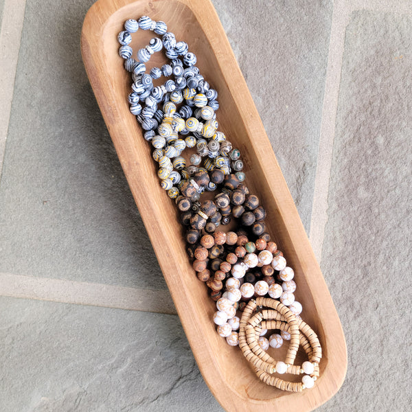 piles of bead stretch bracelets in a wooden bowl