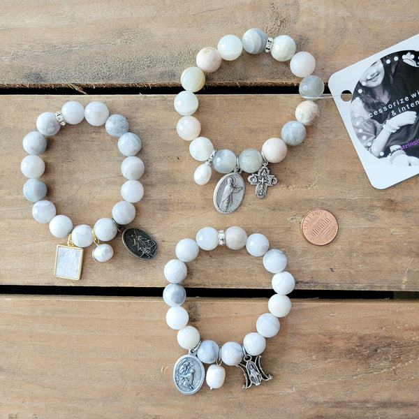 variety of bead bracelets each with 3 charms / medals