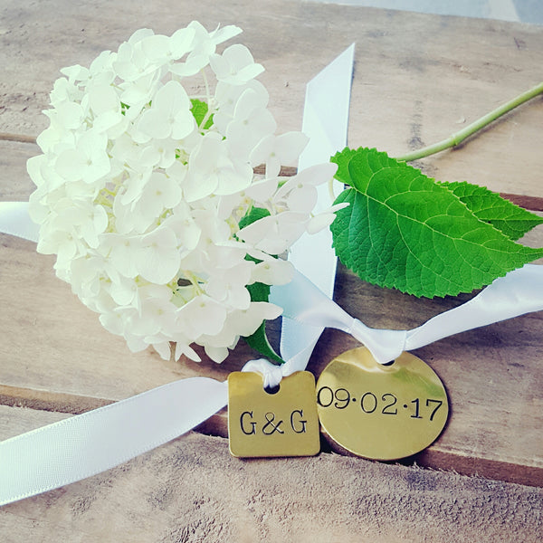 vintage hand stamped wedding dates on brass tags tied on a white ribbon